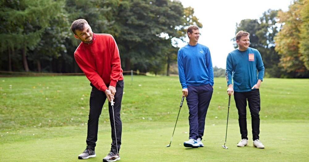 Three men all playing golf together