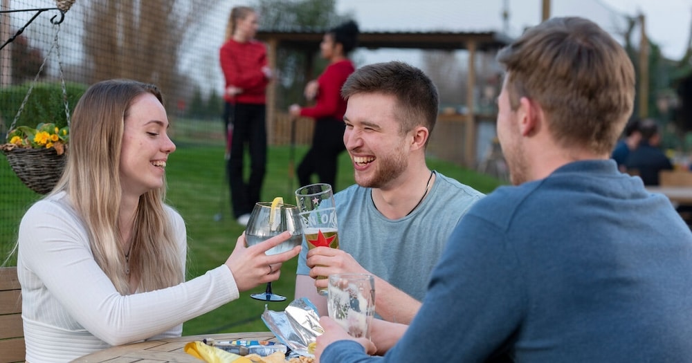 Sociable Golf Taster Sessions with a group of adults drinking with the golf course in the background.