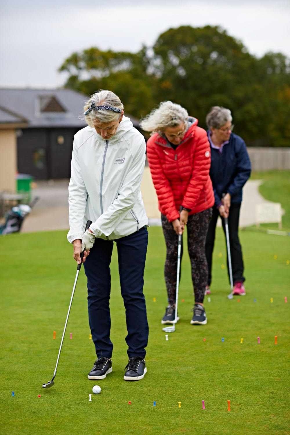 Three women all practicing their putting