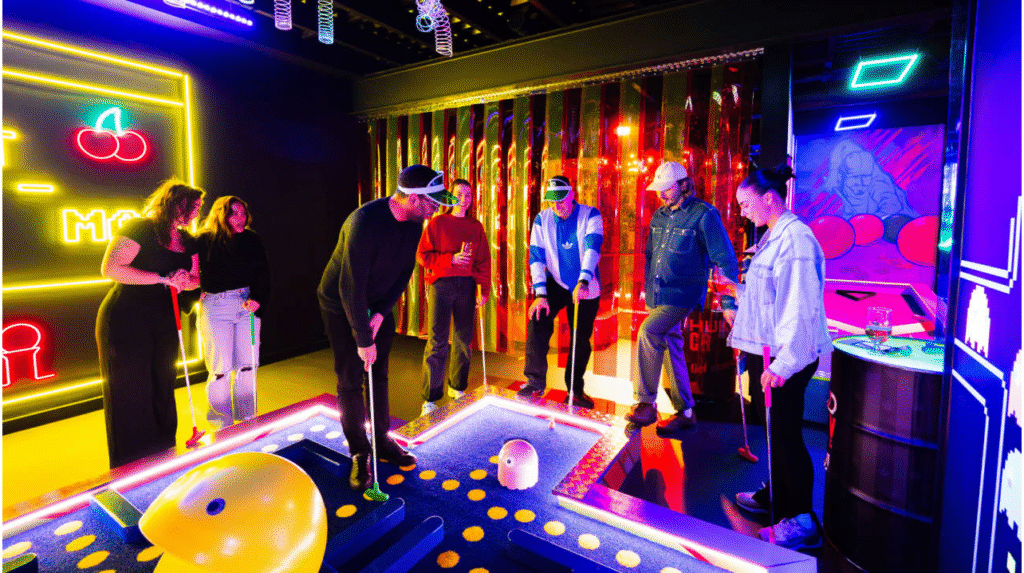 Group of friends playing neon mini golf in an arcade-style glow-in-the-dark venue.